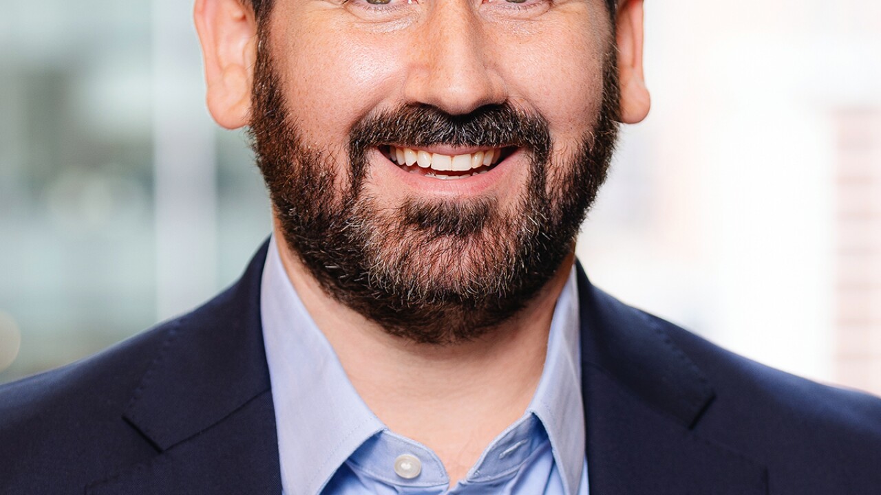 A man in a suit coat smiles for a photo.