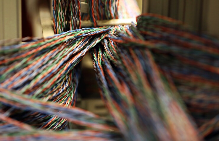 Twisted copper wiring sits in an electrical unit inside a communications room at an office in London.