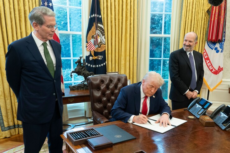 President Donald Trump signs an executive order during a ceremony with Scott Bessent, U.S. Treasury secretary, left, and Howard Lutnick, chief executive officer of Cantor Fitzgerald LP and U.S. commerce secretary nominee, right, in the Oval Office of the White House.