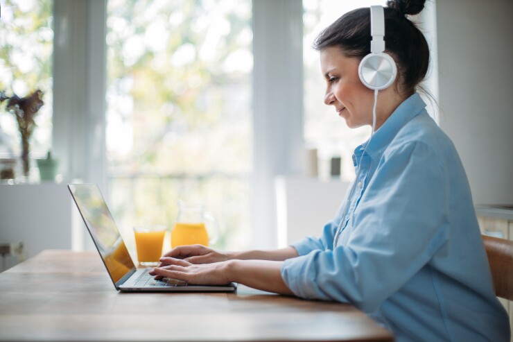 Woman sitting in front of her laptop with headphones on