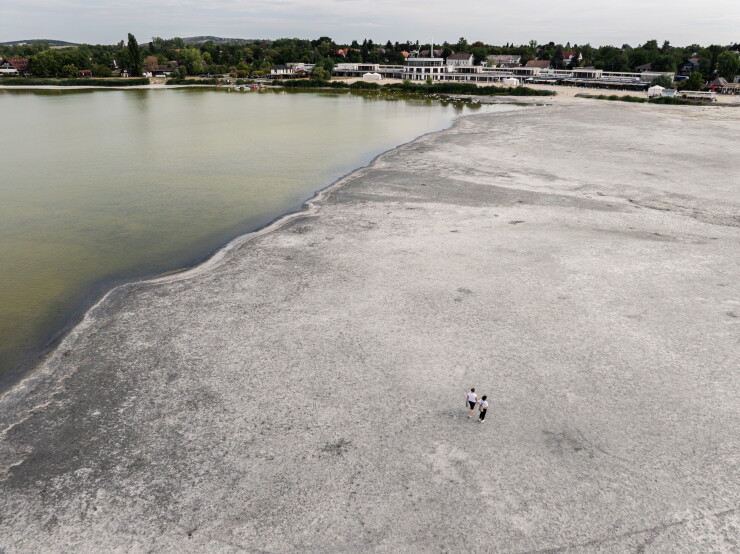 People walk across the exposed lakebed from low water levels during a heat wave on Lake Velence, Hungary.