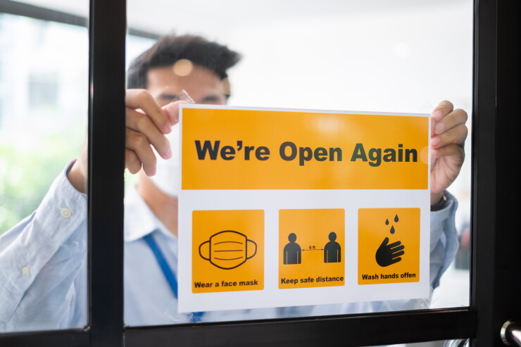 Asian businessman wear face mask attach reopen sign at office af