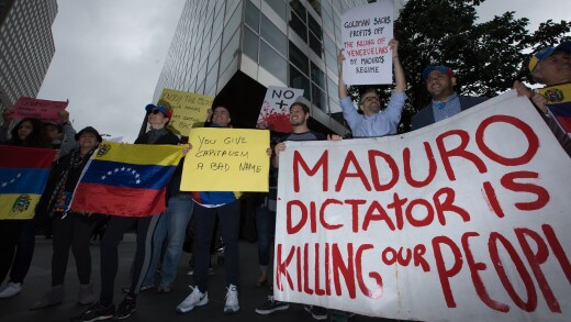 Demonstrators hold signs and Venezuelan flags during a protest outside of the Goldman Sachs headquarters in New York.