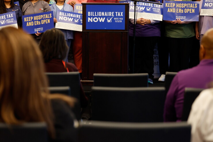 Supporters hold signs advocating for the Billionaire Tax Now coalition during a news conference in Los Angeles.