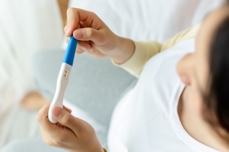 Woman looking down at a positive pregnancy test