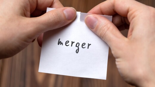 Hands of a man tearing a piece of paper with inscription merger