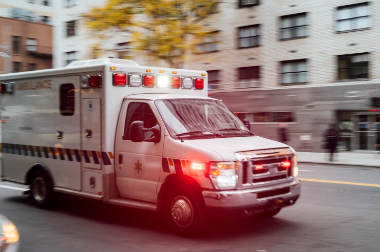 An ambulance flashing red lights goes down a New York City street.