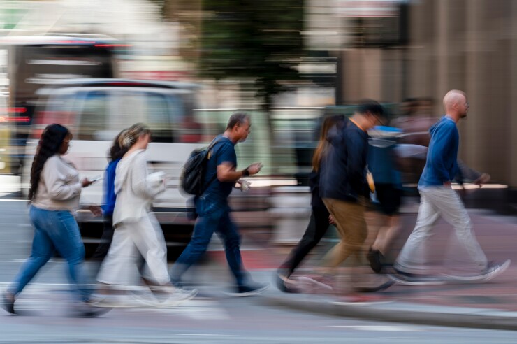 Commuters walk across the street.