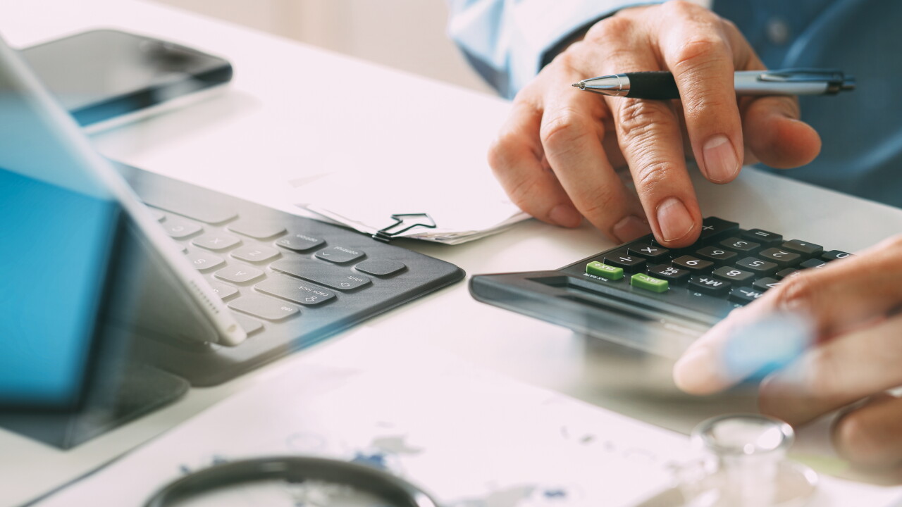 Healthcare costs and fees concept. Hand of smart doctor used a calculator for medical costs in modern hospital.