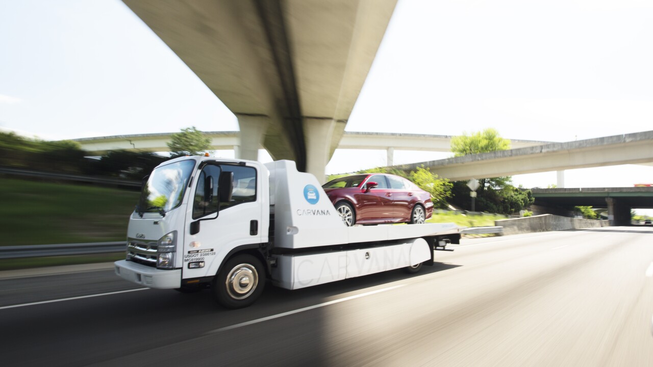 A Carvana truck delivering a vehicle purchased through the company's online portal.