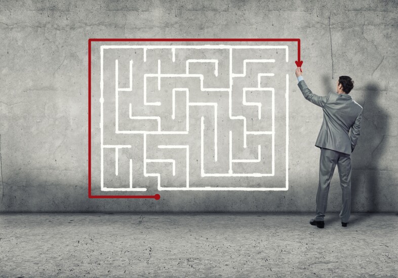 Businessman showing a route around maze instead of through it.
