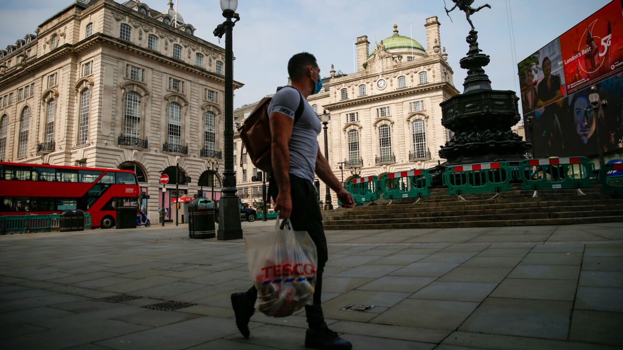 A pedestrian carries a Tesco Plc shopping bag in view of the Statue of Eros in Piccadilly Circus in London, U.K., on Friday, Sept. 11, 2020. Britain recorded strong economic growth in July as coronavirus restrictions eased, but mounting job losses and the risk of a messy Brexit are threatening a turbulent end to the year. Photographer: Hollie Adams/Bloomberg