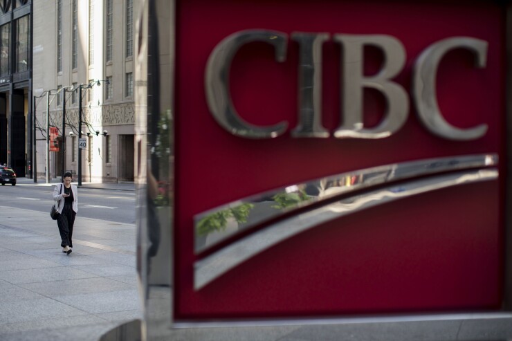 A pedestrian walks past a Canadian Imperial Bank of Commerce sign outside the company's headquarters in the financial district of Toronto.