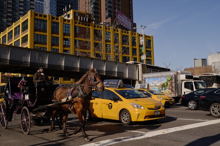 Vehicles drive past a horse-drawn carriage on 10th Avenue near the Lincoln Tunnel in New York, U.S., on Tuesday, April 2, 2019.