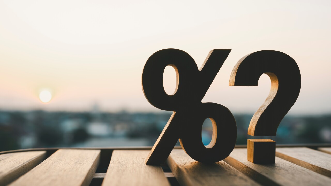 Percentage and question mark on wood table in blur urban background, raising or lowering Fed interest rates to correct inflation concepts.