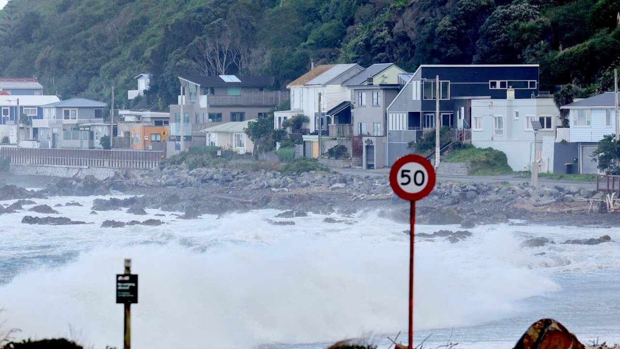 Waves on a beach with houses in the background.