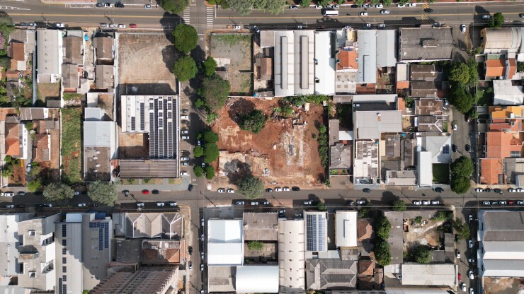 Aerial photo of an empty lot, several houses and commercial buildings