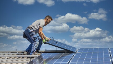 Solar panel technician installing solar panels on roof.