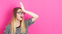 Young woman making a mistake on a pink background