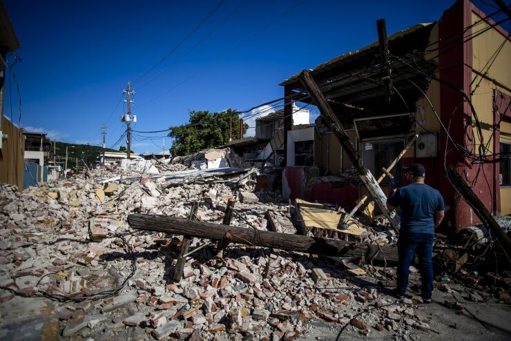 A person inspects rubble and destroyed power lines in Guayanilla, Puerto Rico, on Sunday, Jan. 12, 2020. Puerto Rico was hit by a series of earthquakes over the preceding 15 days