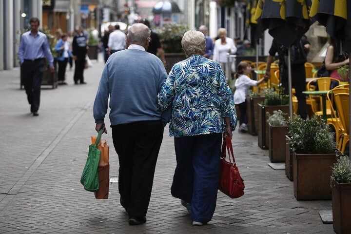 An elderly couple walk arm-in-arm past an outdoor cafe terrace in Edinburgh, U.K., on Wednesday, July 31, 2013. The latest opinion polls show supporters of Scottish First Minister Alex Salmond's campaign for independence lagging behind those in favor of the status quo by more than 20 percentage points ahead of the Sept.18, 2014, referendum. Photographer: Simon Dawson/Bloomberg