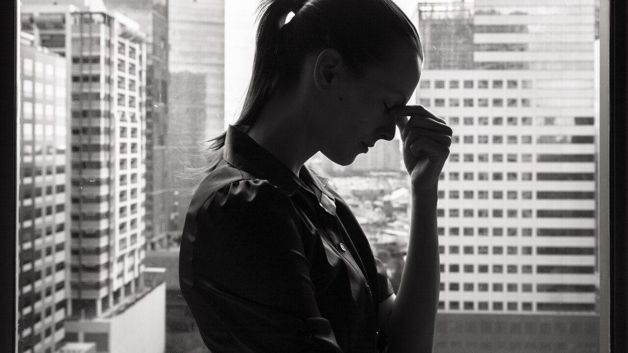 Woman in office, stressed, fingers pressed on bridge of nose