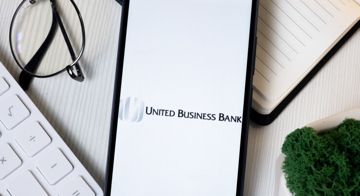 BayCom Logo on Phone Screen, United Business Bank Company Icon