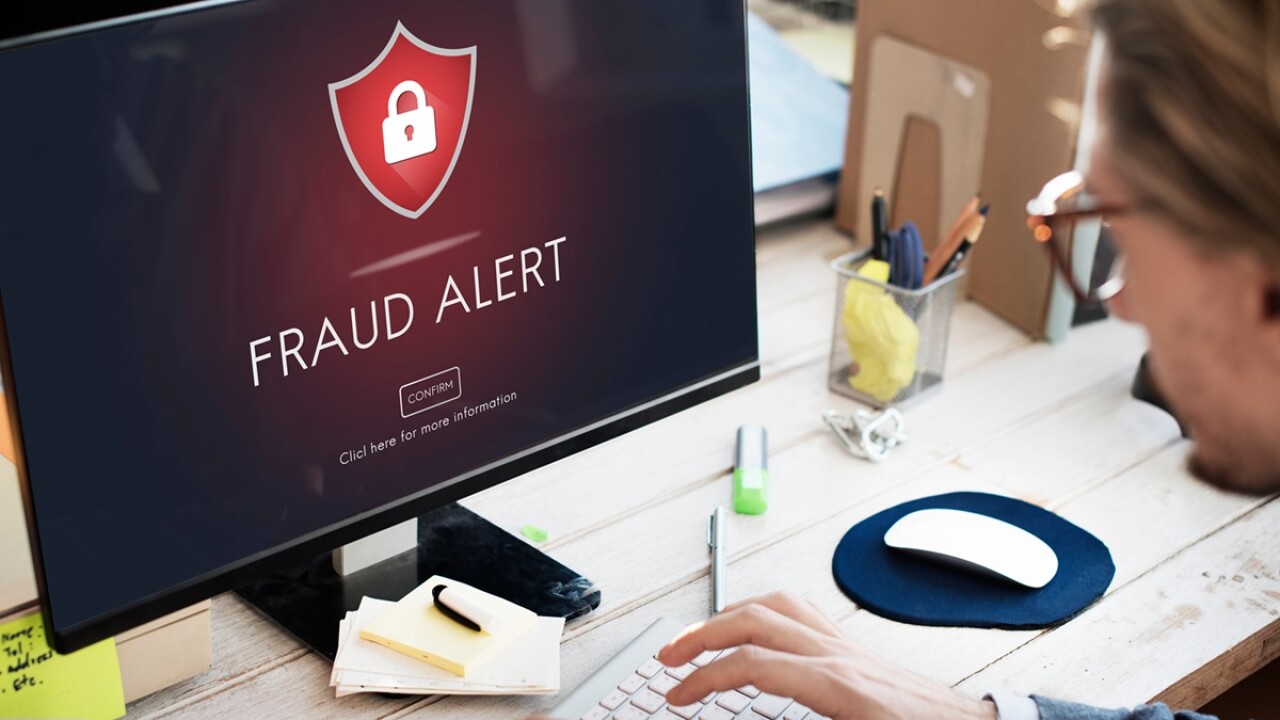 Person sitting in front of a computer that say fraud alert.