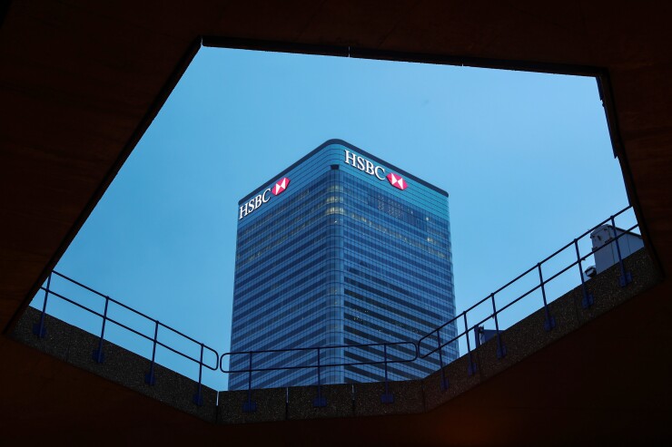 Logos sit illuminated on the HSBC headquarter skyscraper offices in the Canary Wharf business, financial and shopping district in London.