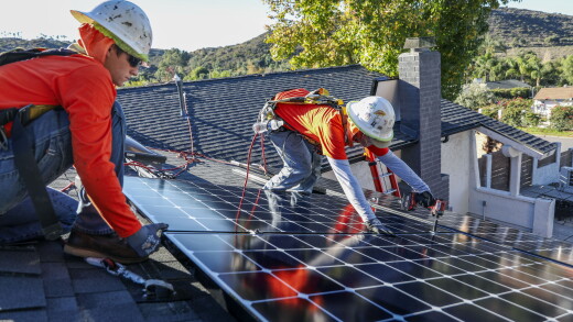 Workers install solar panels on the roof of a home in Poway, California.