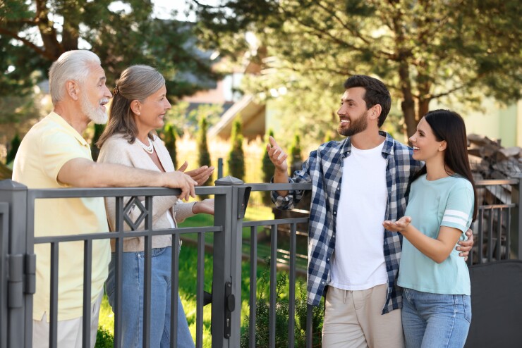 Four people conserving with a fence in between them.