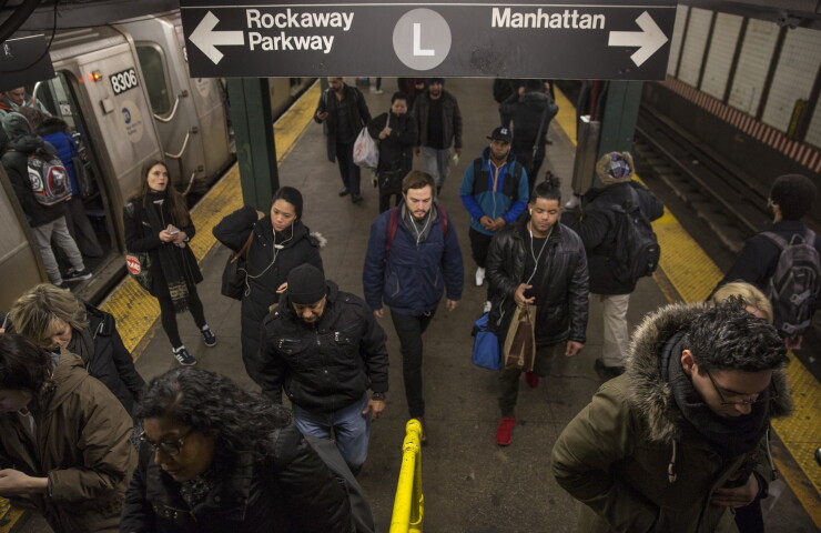 Commuters exit an L train at the Bedford Avenue subway station in the Brooklyn borough of New York, U.S., on Wednesday, Dec. 20, 2017.
