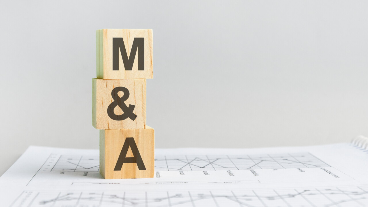 Wooden block with words M&A for mergers and acquisitions. M&A wooden blocks on a paper with a gray background business concept