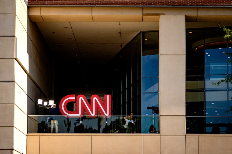 CNN logo (the words CNN in red with a white line in the middle of said words) at the top of a building during the day.
