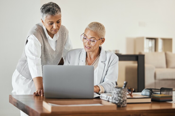 Two female employees looking at laptop on desk
