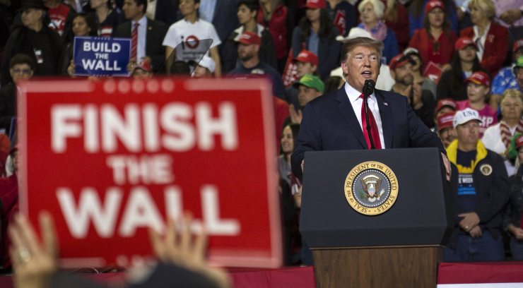 An attendee holds a banner reading "Finish the Wall" as U.S. President Donald Trump speaks during a rally in El Paso, Texas, U.S., on Monday, Feb. 11, 2019.