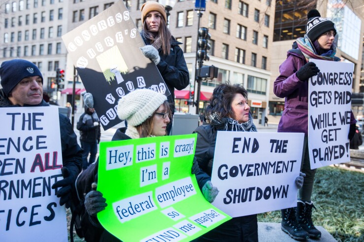 Demonstrators hold signs in Boston during a protest against the government shutdown.