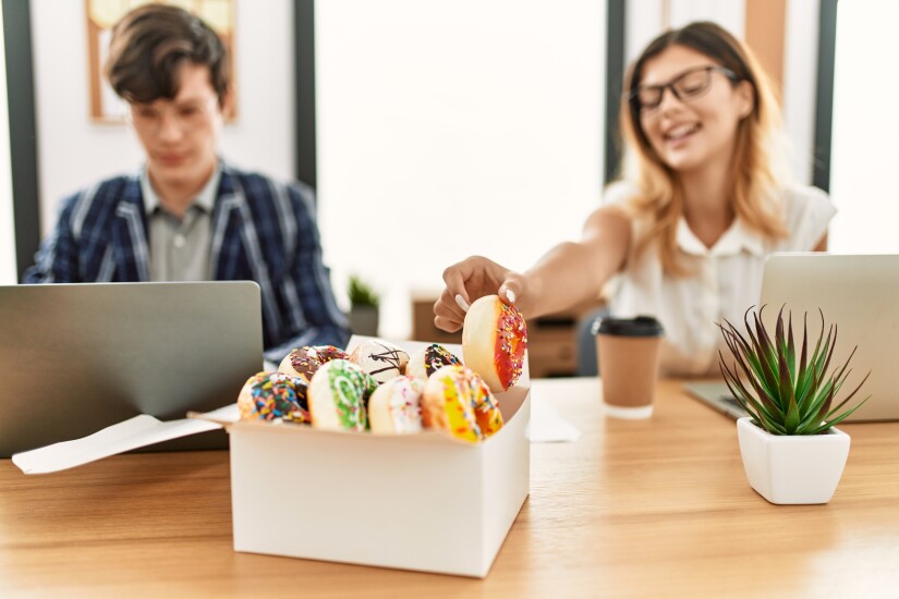 Employee reaching for donut while working