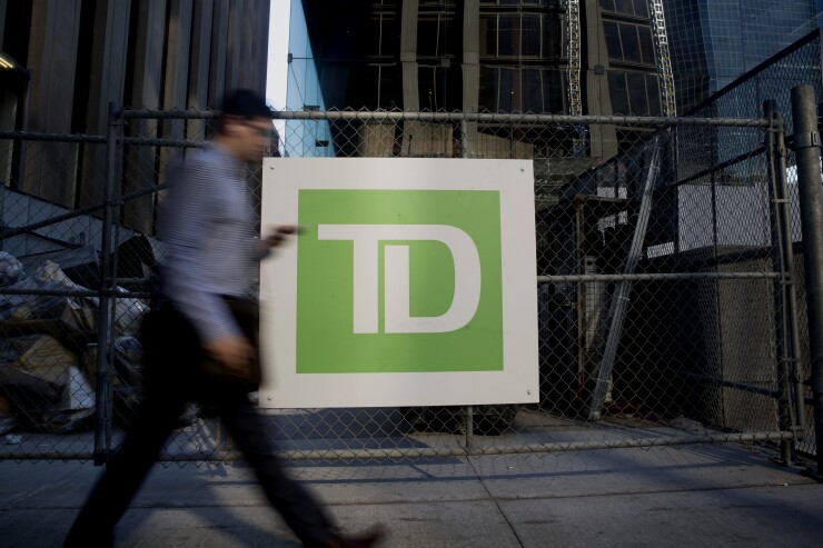 A commuter walks past Toronto-Dominion Bank signage in the financial district of Toronto.