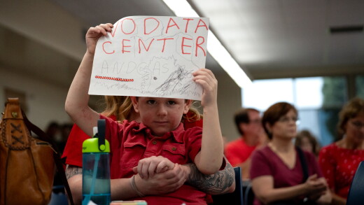 A boy holds a "No data center" sign