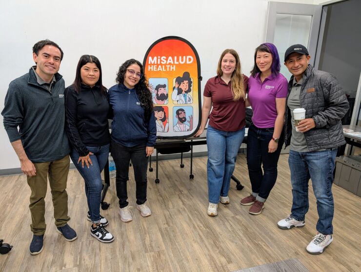 Six people stand around a sign that says MiSalud Health.