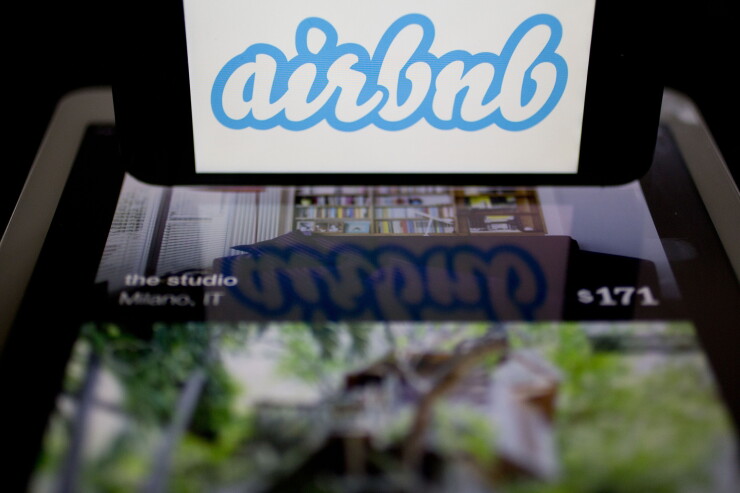The Airbnb logo and app displayed on an Apple iPhone and iPad