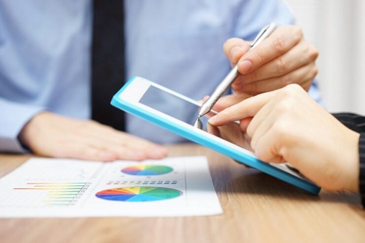 Two people looking at a tablet overlooking a page with two circle graphs.