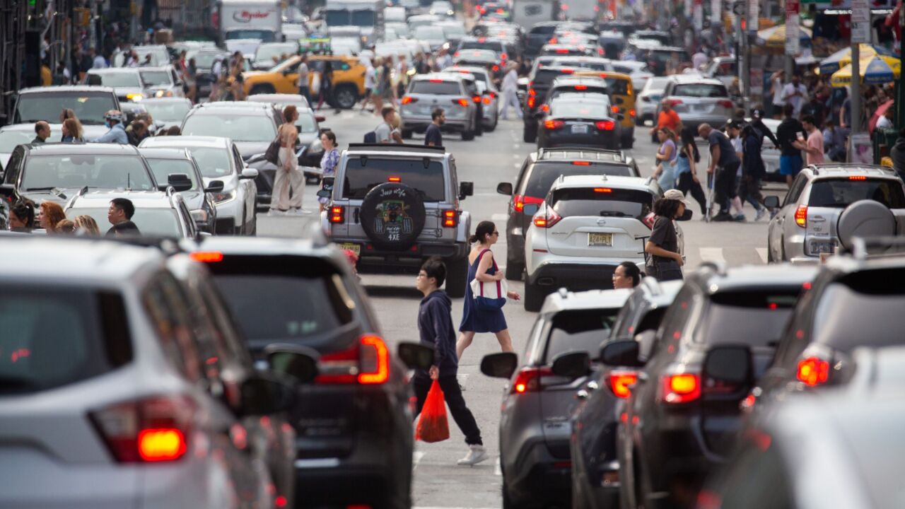 Pedestrians cross a street past traffic in the Chinatown neighborhood of New York, US, on Saturday, June 17, 2023. New York City's congestion pricing plan for the central business district is expected to get final approval this month. Photographer: Michael Nagle/Bloomberg