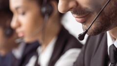 Close-up image of two workers, wearing headsets, at a call center.