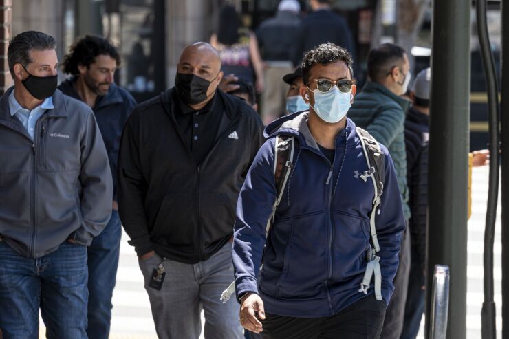 People wearing protective masks walk on Columbus Avenue in San Francisco, California, U.S., on Thursday, May 6, 2021. San Francisco advanced into the least restrictive tier of California’s color-coded reopening system Tuesday, allowing most businesses to expand capacity, bars to start serving indoors and large gatherings to resume inside and outside. Photographer: David Paul Morris/Bloomberg