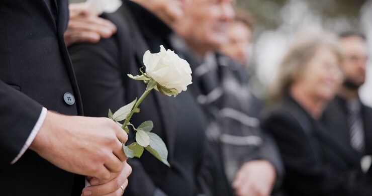 A person holds a flower at a funeral service.