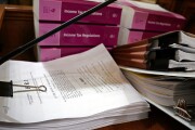 A printout of Congress's tax reform bill, "The Tax Cuts and Jobs Act," alongside a stack of income tax regulations