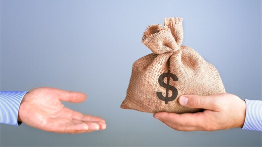 One hand offering a bag of money with the other accepting it