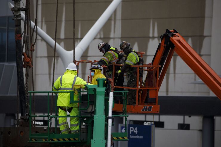 A contractor wearing a protective mask works on an automated people mover under construction in the central terminal area at Los Angeles International Airport (LAX) in Los Angeles, California, U.S., on Thursday, April 9, 2020. Passenger traffic has fallen about 95% compared with a year ago, according to the Transportation Security Administration. Photographer: Patrick T. Fallon/Bloomberg